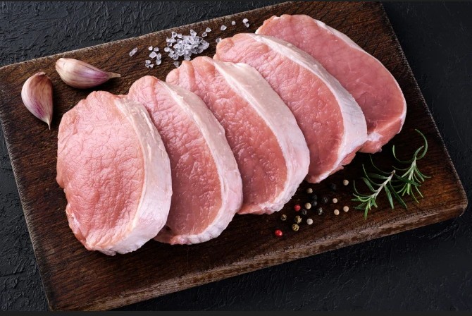 Fresh bone-in pork loin chops on a wooden board
